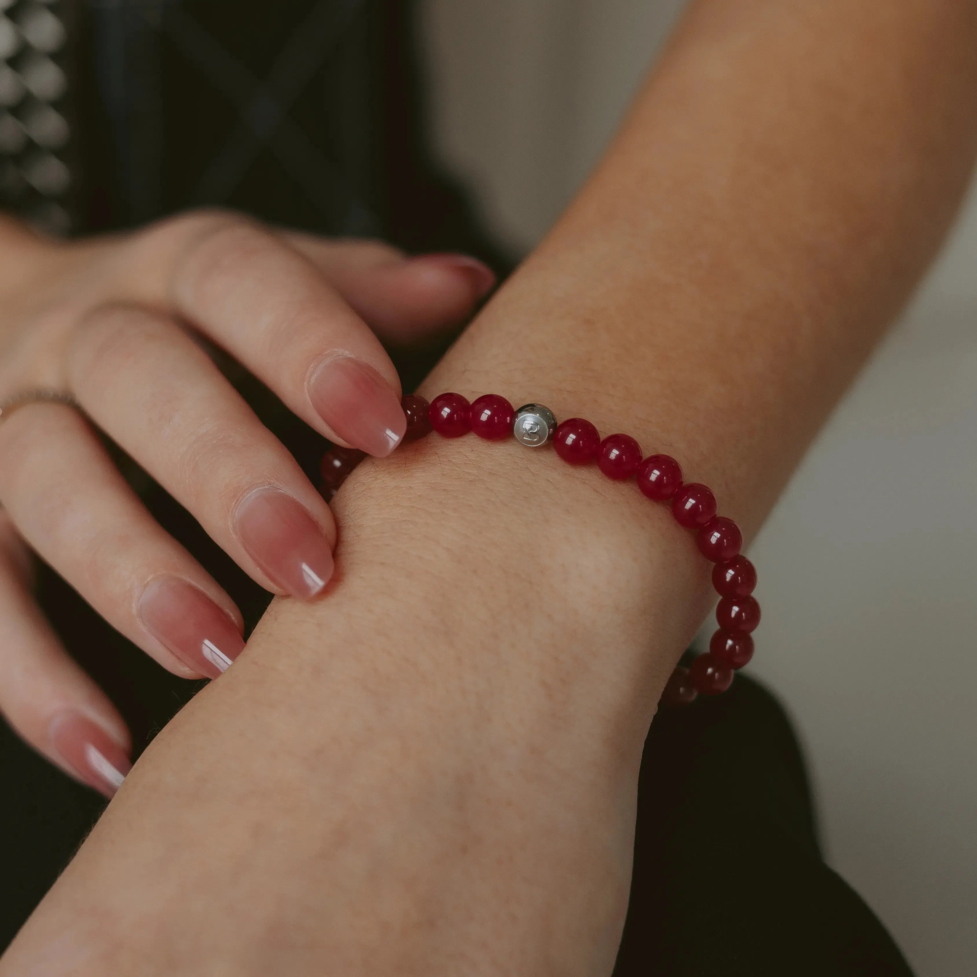 Red ruby 6mm beaded bracelet with silver accent beads and a BOLDN logo charm, displayed on a white background