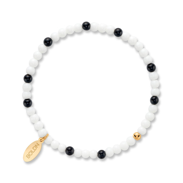 Beaded bracelet with black and white beads and gold accents on a white background